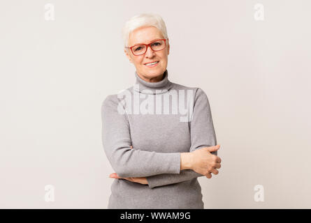 Certain femme âgée dans les verres debout les bras croisés Banque D'Images