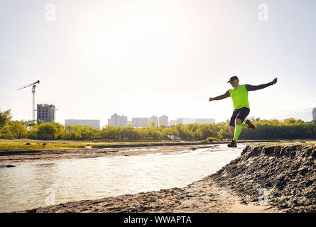 Personnes âgées man running in park, près de la rivière avec des bâtiments et l'arrière-plan la montagne le matin. Concept de vie sain Banque D'Images