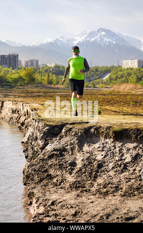 Un homme âgé de près de la rivière avec des bâtiments et l'arrière-plan la montagne le matin. Concept de vie sain Banque D'Images