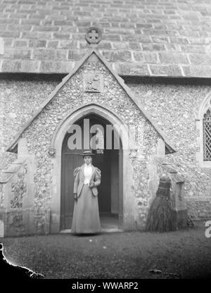 La fin de l'ère victorienne ou édouardienne précoce dame debout dans une église porte Banque D'Images