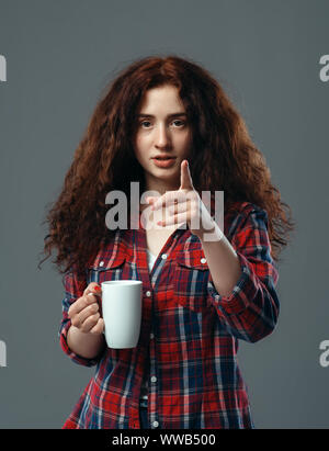 Jeune femme avec tasse de café sur fond gris Banque D'Images