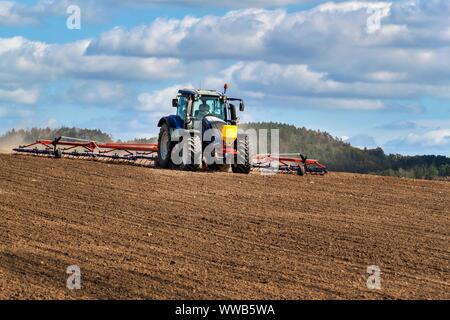 Un tracteur bleu sème le grain. Travail agricole sur une ferme de la République tchèque. Le tracteur sur un champ de blé. Les machines agricoles. Banque D'Images