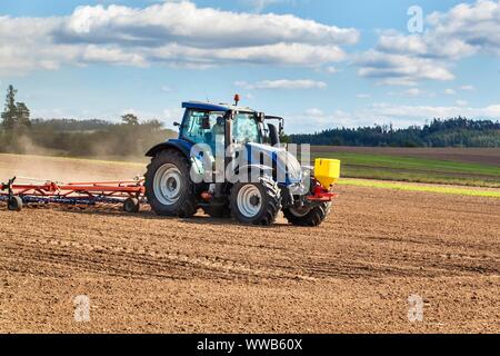 Un tracteur bleu sème le grain. Travail agricole sur une ferme de la République tchèque. Le tracteur sur un champ de blé. Les machines agricoles. Banque D'Images