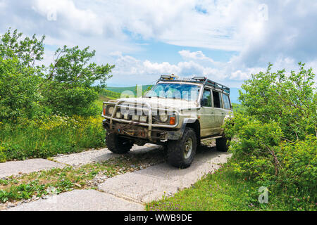 Mnt. Runa, Ukraine - JUN 19, 2019 : ancien véhicule hors route sur la montagne route pavée. sale SUV préparé pour la bataille avec la nature. Mountain dans le dis Banque D'Images