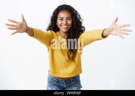 Viens ici dans mes bras. Gai friendly-à pretty african american woman en jaune chandail, propagation dans les mains accueil chaleureux, souriant joyeusement Banque D'Images