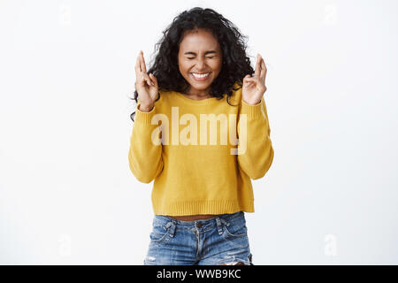 Girl pense que les rêves peuvent se réaliser, qui souhaitent amener le Père Noël cadeau pour Noël, fermer les yeux en souriant joyeusement, les doigts bonne chance, l'anticipation positive Banque D'Images