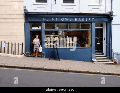 Personne sortant de Flint Owl Bakery sur Inclued High Street, Lewes, transportant du pain acheté à l'établissement. Lewes, High Street Banque D'Images