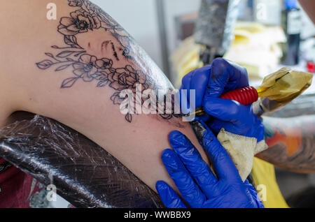 WROCLAW, Pologne - 11 août 2019 : concours de tatouage. Processus de tatouage floral sur une femme bras supérieur. Close-up, selective focus Banque D'Images