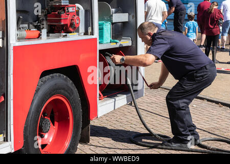 Un pompier britannique tirant un flexible d'un incendie Banque D'Images