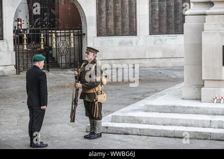 Un homme de la première guerre mondiale uniforme des soldats de la remise d'une veillée d'un ancien combattant de la guerre moderne à un monument commémoratif de guerre Banque D'Images