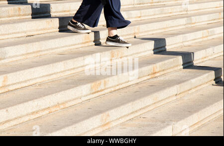 Les jambes de jeune femme chaussures sneaker en descendant les escaliers de la ville sur une journée ensoleillée Banque D'Images