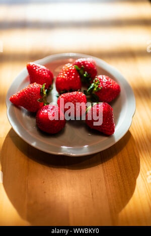 Gros plan macro dessert traditionnel japonais cher dodu fraises à l'assiette à table en bois dans la cuisine avec la lumière du soleil Banque D'Images