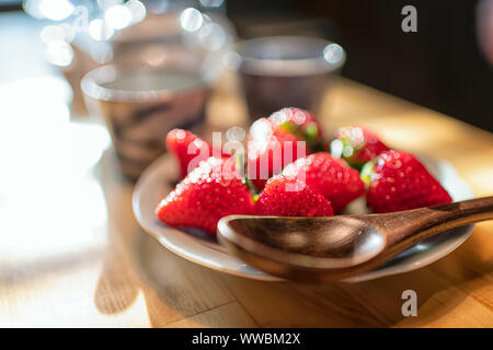 Dessert traditionnel japonais cher dodu fraises à l'assiette à table en bois dans la cuisine avec deux tasses de thé, une théière avec du thé vert en haut trouble Banque D'Images