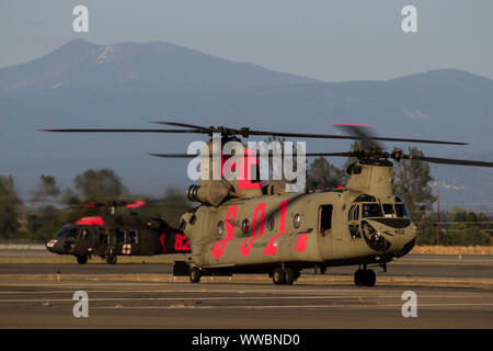 L'Armée américaine Un hélicoptère CH-47 Chinook de l'Armée de la Garde nationale de Californie de la Compagnie Bravo, 1er Bataillon, 126e Régiment d'aviation, et l'hélicoptère UH-60 Black Hawk de l'Armée de Mather et de soutien à l'Aéroport Municipal de Redding, le 8 septembre 2019, dans la région de Redding, en Californie, après avoir travaillé la Banque rouge feu brûler dans le comté de Tehama. Six hélicoptères ont été activés Cal Garde côtière canadienne pour aider les organismes fédéraux et d'État pour combattre une paire de feux de forêt dans le comté. (U.S. Photo de la Garde nationale aérienne par le sergent. Housman Crystal) Banque D'Images