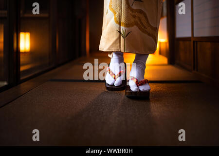 Maison traditionnelle japonaise ryokan libre avec tatami, plancher portes coulissantes shoji en papier et femme kimono geta et tabi chaussettes chaussures de marche dans le co Banque D'Images