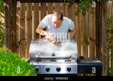 Barbecue grill nouveau moderne dans l'air extérieur nature été jardin arrière pendant la journée avec l'homme debout se préparer la température Banque D'Images
