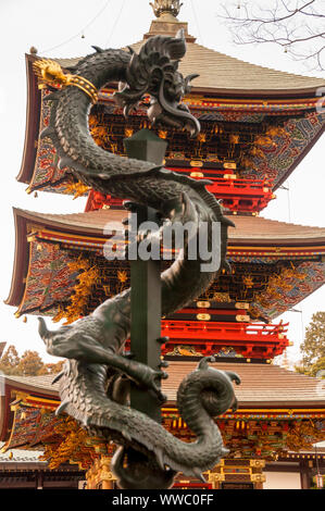 Pagode Sanju-no-to de trois étages de l'ère Edo dans le complexe du temple Naritasan à Narita, au Japon, avec une statue de dragon du cimetière en forteresse. Banque D'Images