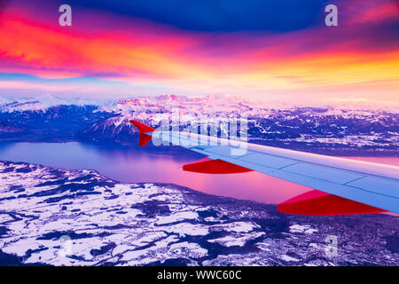 Vue imprenable depuis la fenêtre de l'avion pendant le coucher de soleil sur Alpes en Suisse Banque D'Images