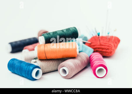 Outils pour la couture, tricot rouge coussin d'aiguille pour coudre et bobines fil de couleur sur fond blanc avec copie espace pour le texte Banque D'Images