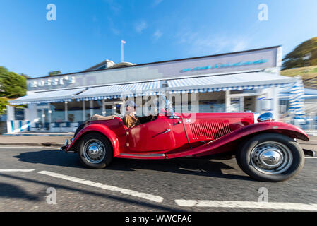 Classic and vintage cars ont dirigé le long du front de mer de la ville balnéaire de prendre part à un "show 'n' shine" événement à City Beach sur Marine Parade à Southend on Sea, Essex. Le Royaume-Uni s'est levé par temps clair, chaud et ensoleillé. Vintage voiture passe Rossi ice cream parlour Banque D'Images