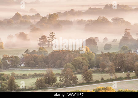 Firle, Lewes, East Sussex, Royaume-Uni. 15 septembre 2019. Brouillard lent à disparaître dans la douce brise du nord-Est lorsque le soleil se lève et jette son éclat orange. Scènes éthérées dans la magnifique campagne du Sussex. . Banque D'Images