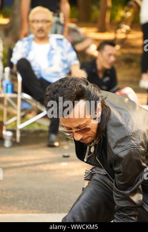 Un homme japonais membre des étrangers, un Tokyo Rockabilly Club, avec un pompadour et une veste et pantalon en cuir noir dansant au parc Yoyogi. Banque D'Images