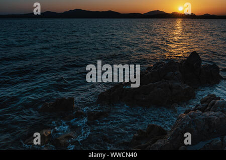 Beau coucher de soleil méditerranéen avec du soleil et des rochers en premier plan Banque D'Images