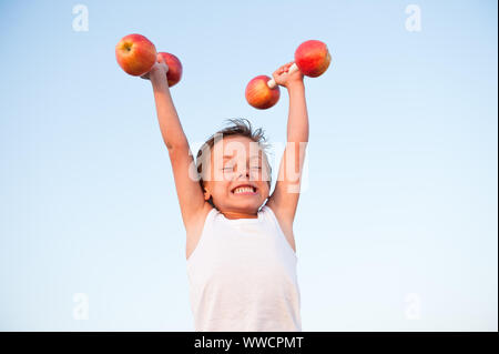 Peu solide caucasian boy in débardeur blanc lever les haltères d'entraînement pendant la formation Apple Banque D'Images