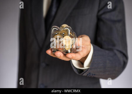 L'homme d'affaires avec veste gris mettre euro pièce dans la banque piggi. Service des finances de l'Union européenne. Guy holding money box Banque D'Images
