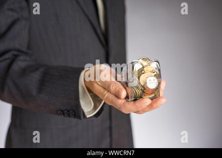 L'homme d'affaires avec veste gris mettre euro pièce dans la banque piggi. Service des finances de l'Union européenne. Guy holding money box Banque D'Images