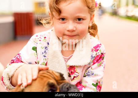 Fille charmante jouit de flatter un chien dans la région de city park. Banque D'Images