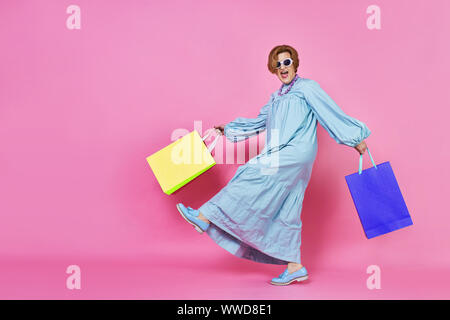 Femme âgée funky avec les achats, Shopaholic, acheté des vêtements, femme Banque D'Images