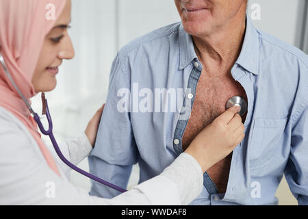 Portrait de femme arabe travailler comme médecin dans une clinique médicale et l'écoute de la respiration et du rythme cardiaque du patient à l'aide de hauts stethoscope Banque D'Images