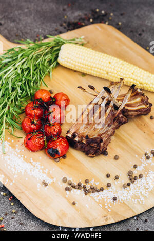 Côtes de la viande avec des légumes sur une planche en bois avec des herbes. Banque D'Images