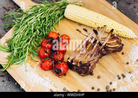 Côtes de la viande avec des légumes sur une planche en bois avec des herbes. Banque D'Images