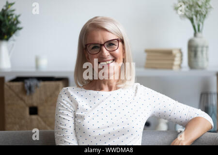 Head shot portrait of smiling mature woman in lunettes à la maison Banque D'Images