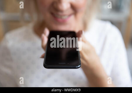 Close up mature woman holding phone, en enregistrant un message Banque D'Images