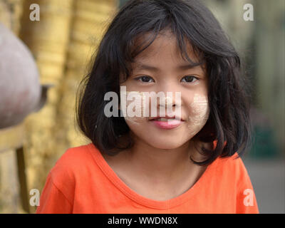 Jolie petite fille birmane avec des taches de blanc jaunâtre visage traditionnel thanaka cosmetic sur ses joues et le nez de sourires pour l'appareil photo. Banque D'Images