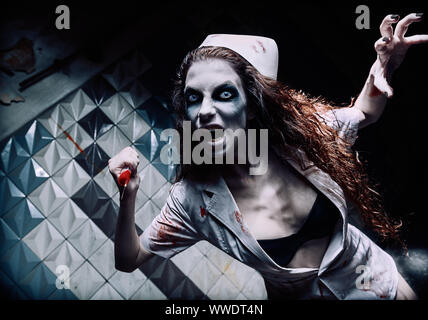 Capture d'horreur : le mal terrible infirmière folle (médecin) attaquer par seringue sanglante. Femme Zombie (morts-vivants). Monstre de cauchemar Banque D'Images