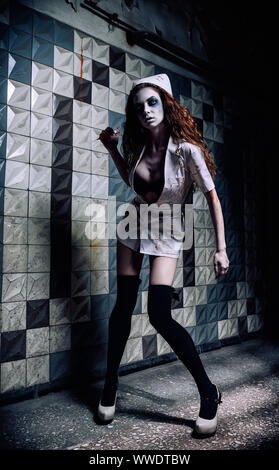 Capture d'horreur : le sombre méchant infirmière folle (médecin) dans bloody uniforme, avec la seringue dans la main. Femme Zombie (morts-vivants) Banque D'Images