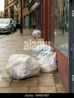 Sacs Poubelles plein de déchets et détritus sur la place à Wigan un dimanche matin Banque D'Images