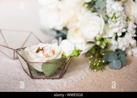 Deux anneaux de mariage dans la belle boîte et bouquet de fleurs. Thèmes de l'engagement, déclaration d'amour, jour de mariage, fleuriste services. Banque D'Images