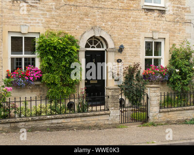 Jolie maison en pierre avec fenêtres à guillotine Fenêtre floraison , paniers Easton sur la Colline, Northamptonshire, England, UK Banque D'Images