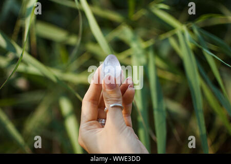 La main féminine avec french manucure holding transparent violet améthyste yoni oeuf pour vumfit imbuilding, ou la méditation. Quartz cristal oeuf dans les mains sur Banque D'Images