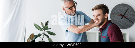 Homme barbu de verres en touchant avec la douleur des patients en clinique Banque D'Images