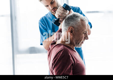 Selective focus of middle aged man exercising with dumbbell près de médecin Banque D'Images