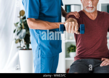 Portrait du docteur debout près de middle aged man exercising with dumbbell Banque D'Images