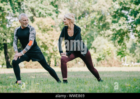 Smiling mature, sportif et de la sportive faisant des exercices de mouvements brusques et regarder dans park Banque D'Images