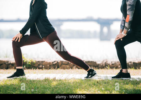 Portrait de sportif et de la sportive faisant des exercices se jette sur Riverside Park Banque D'Images