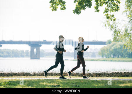 Vue latérale du jogging le long de la maturité sportive dans Riverside Park Banque D'Images